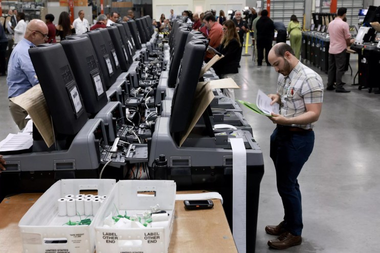County workers hovering around rows of voting machines