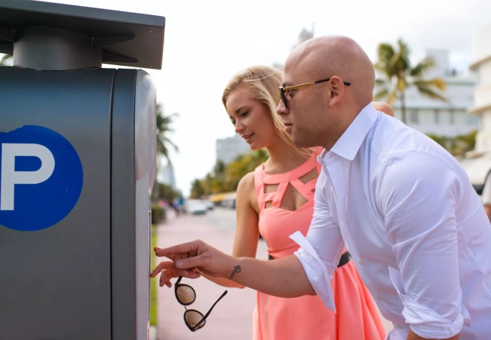 A woman and a man pay at a Pay by Phone meter in Miami Beach
