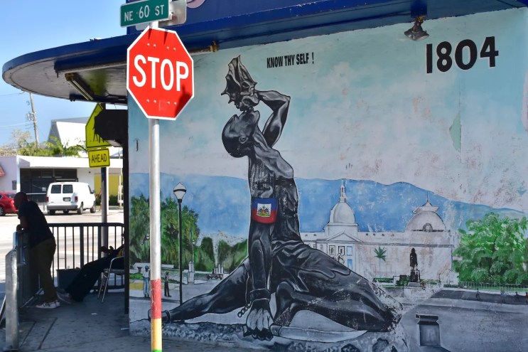 "Know Thy Self": A mural depicting a dark-skinned man with broken shackles holding a machete in one hand and blowing a conch "Freedom Horn" he holds in the other