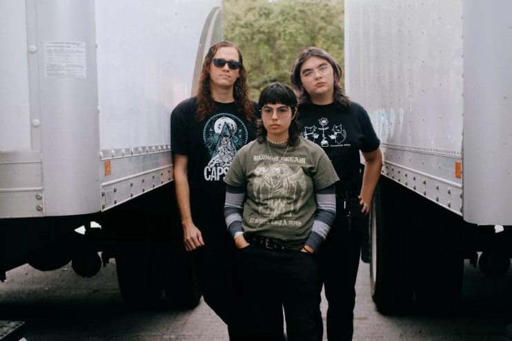 three band members standing next to one another