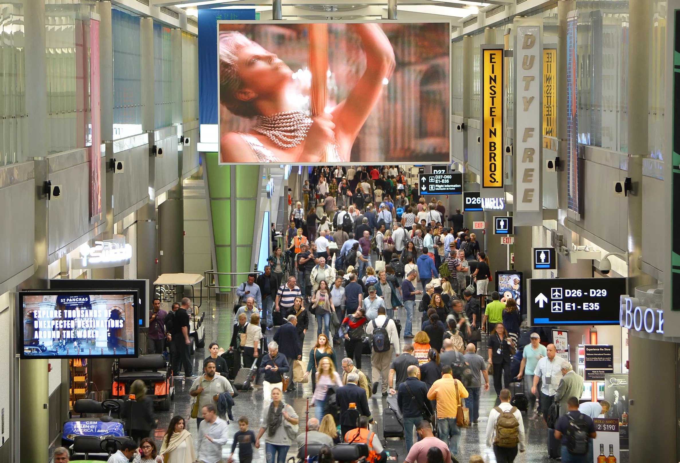 A crowded terminal at Miami International Airport (MIA) with passengers walking through Concourse D, showcasing the airport’s heavy traffic and growing demand