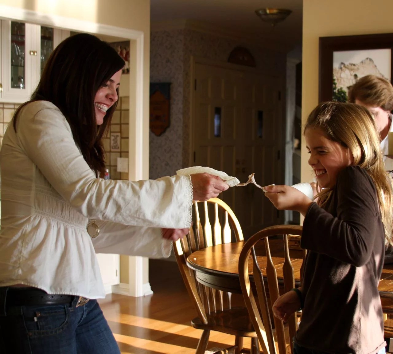 Two people smiling while pulling apart a wishbone, engaging in the traditional wishbone-breaking ritual for good luck