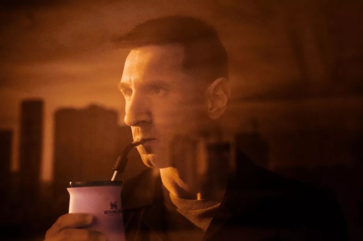 sepia-toned image of leonel messi drinking out of an insulated cup through a straw