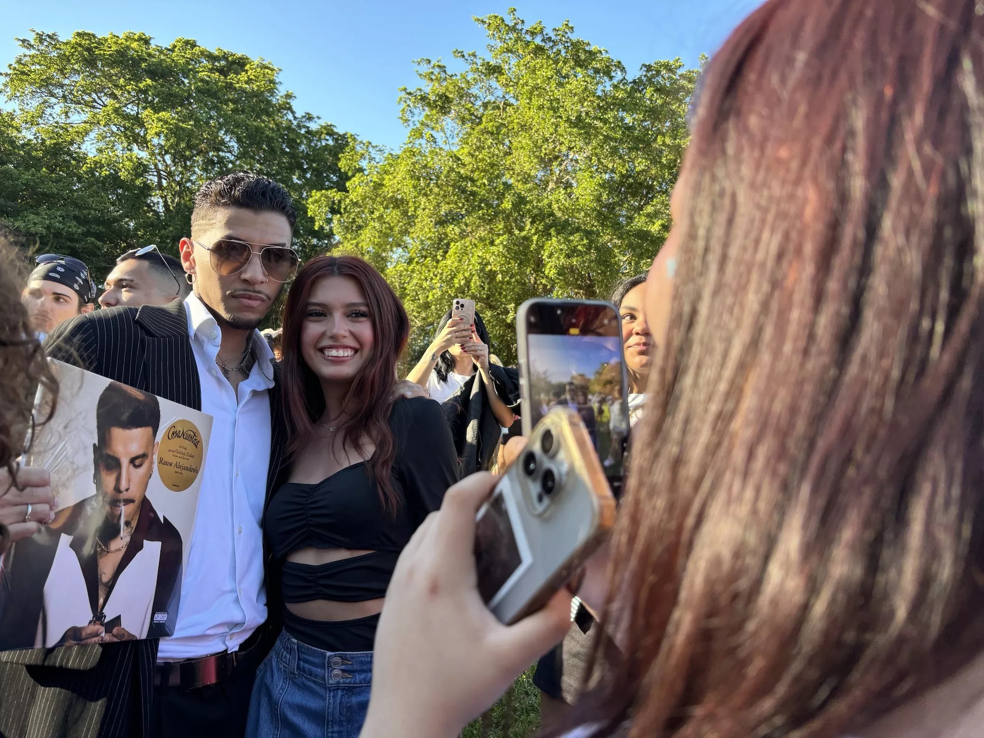 A young man dressed like Rauw Alejandro taking a photo with attendees