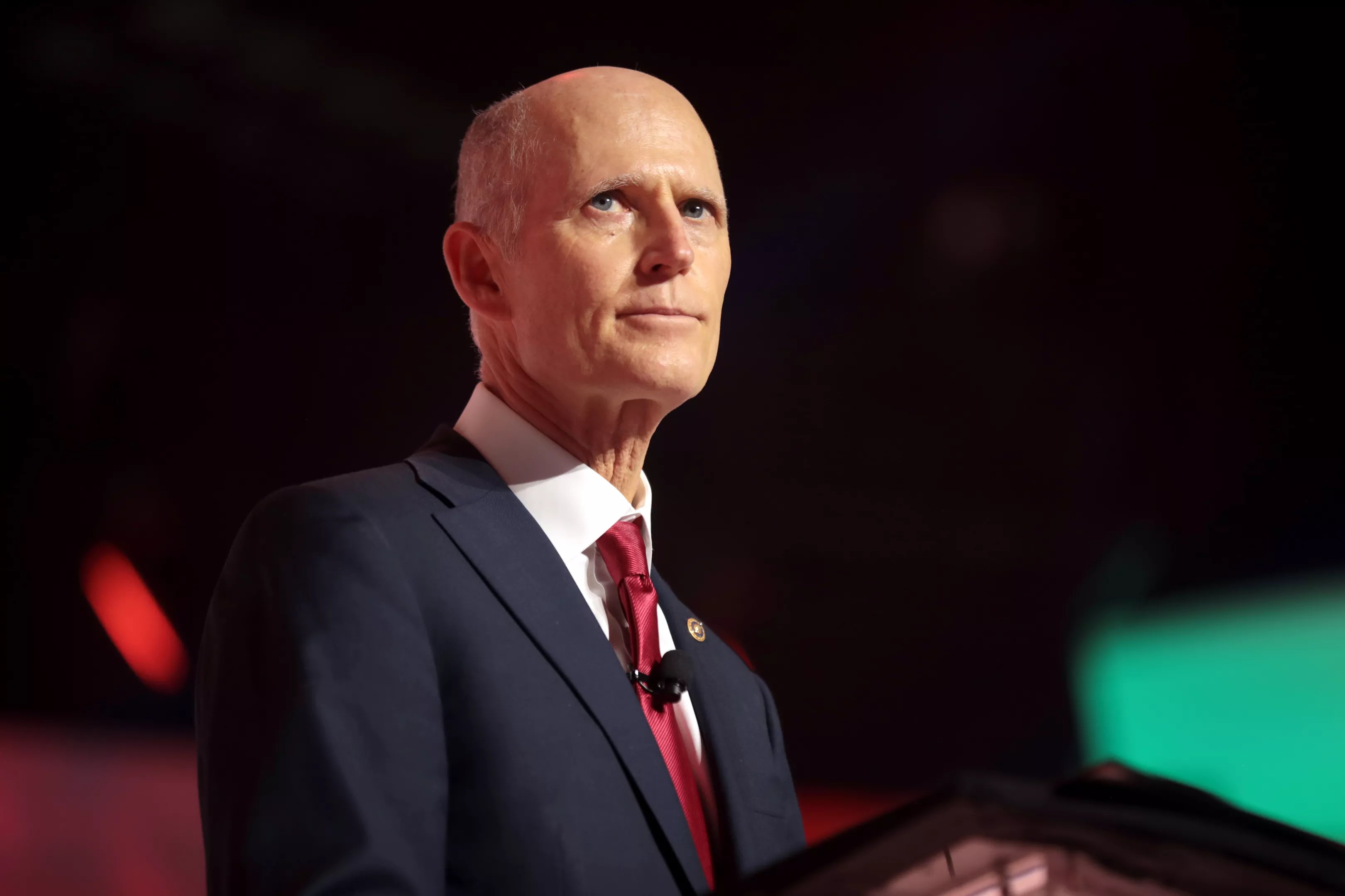 Up-close shot of Rick Scott at a podium looking towards the crowd off to the right.