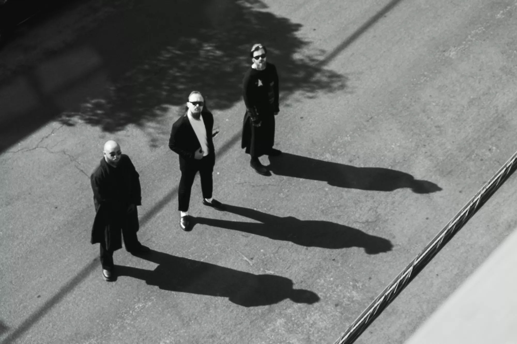 three men standing in the street with their shadows