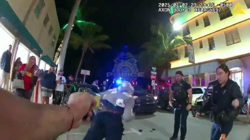 Screenshot from bodycam footage of Miami Beach police using a stun gun on Olympian Fred Kerley during a nighttime arrest with a crowd nearby.