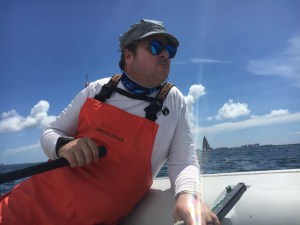 Portrait of man at sea with a sailboat in the background