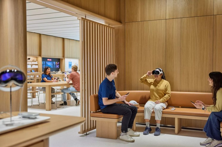 A store employee assists a woman trying out a virtual reality headset