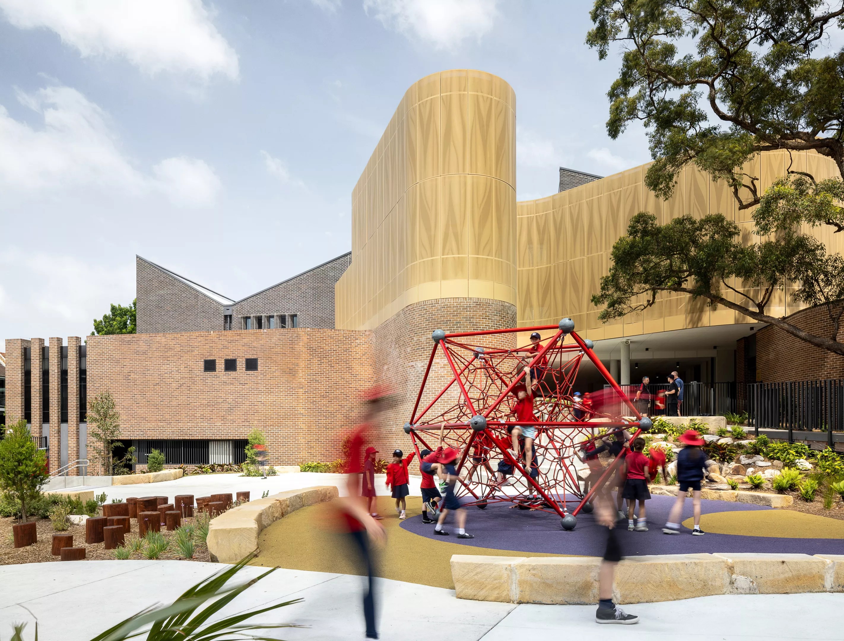 children play on a red jungle gym in front of a building