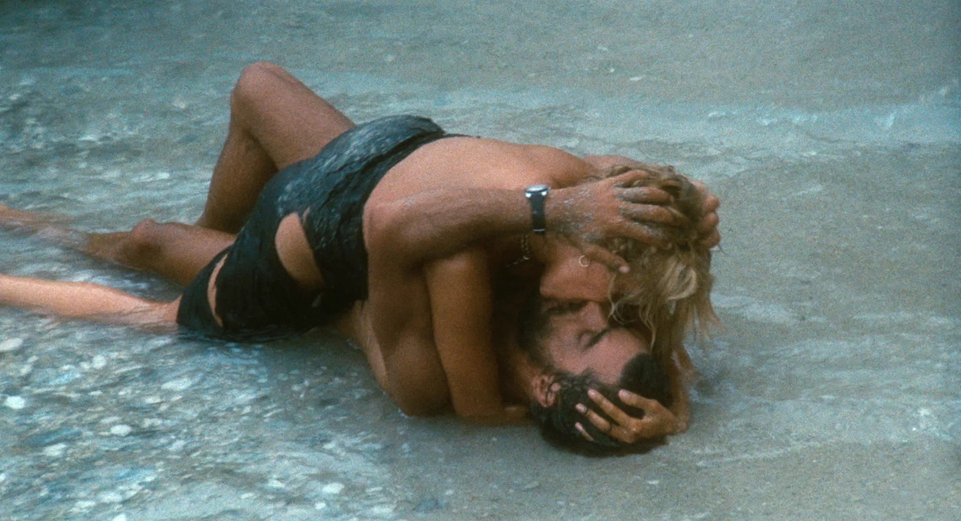 film still from 1974's <i>Swept Away</i>, featuring Raffaella and Gennarino passionately kissing on the beach