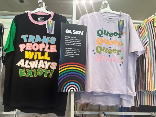 Photo of T-shirts emblazoned with the slogans "Trans People Will Always Exist" and  "Queer Queer Queer Queer! on a Target store rack in Minneapolis in 2023.