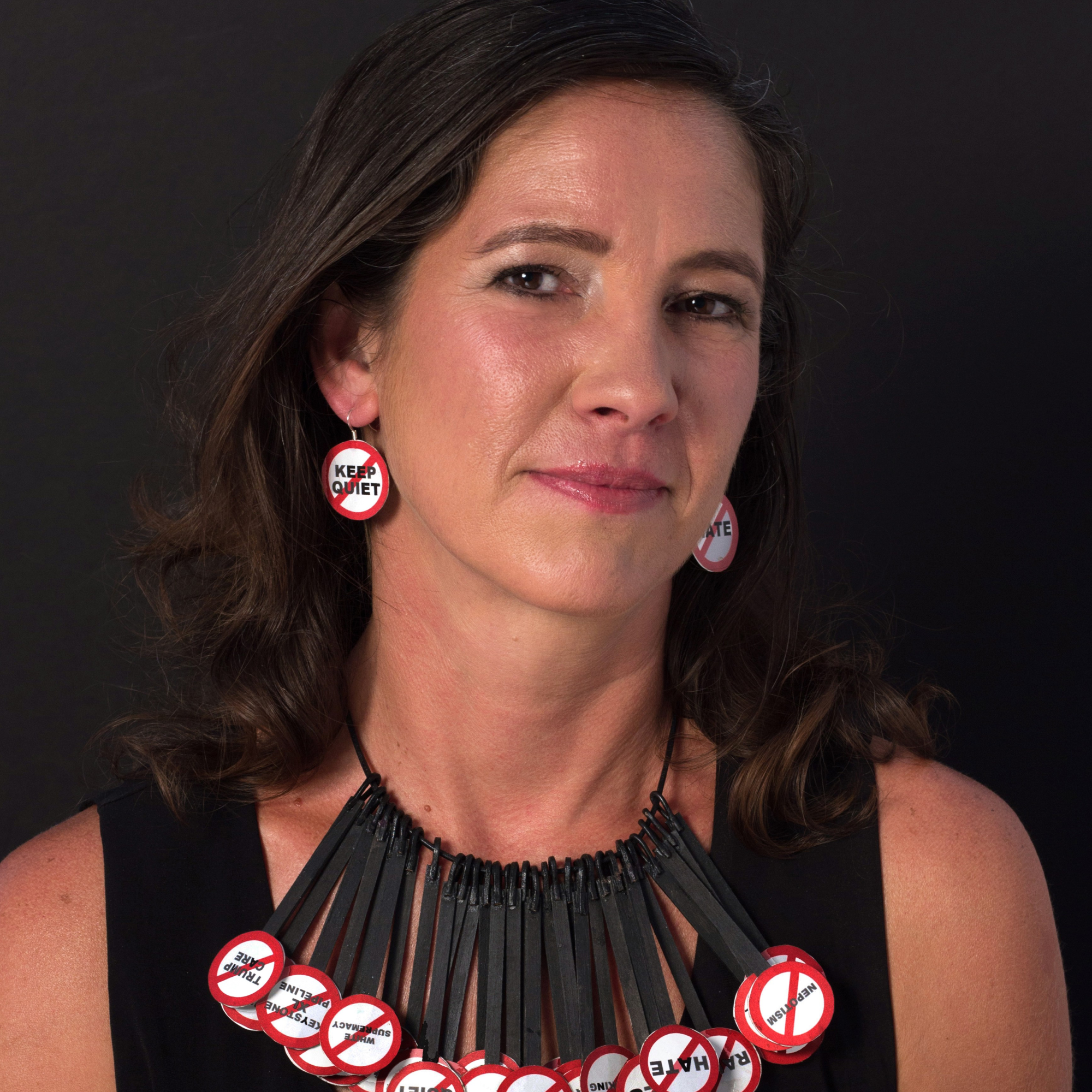 portrait of artist and activist Alessandra Mondolfi wearing earrings and a necklace she created with political messaging