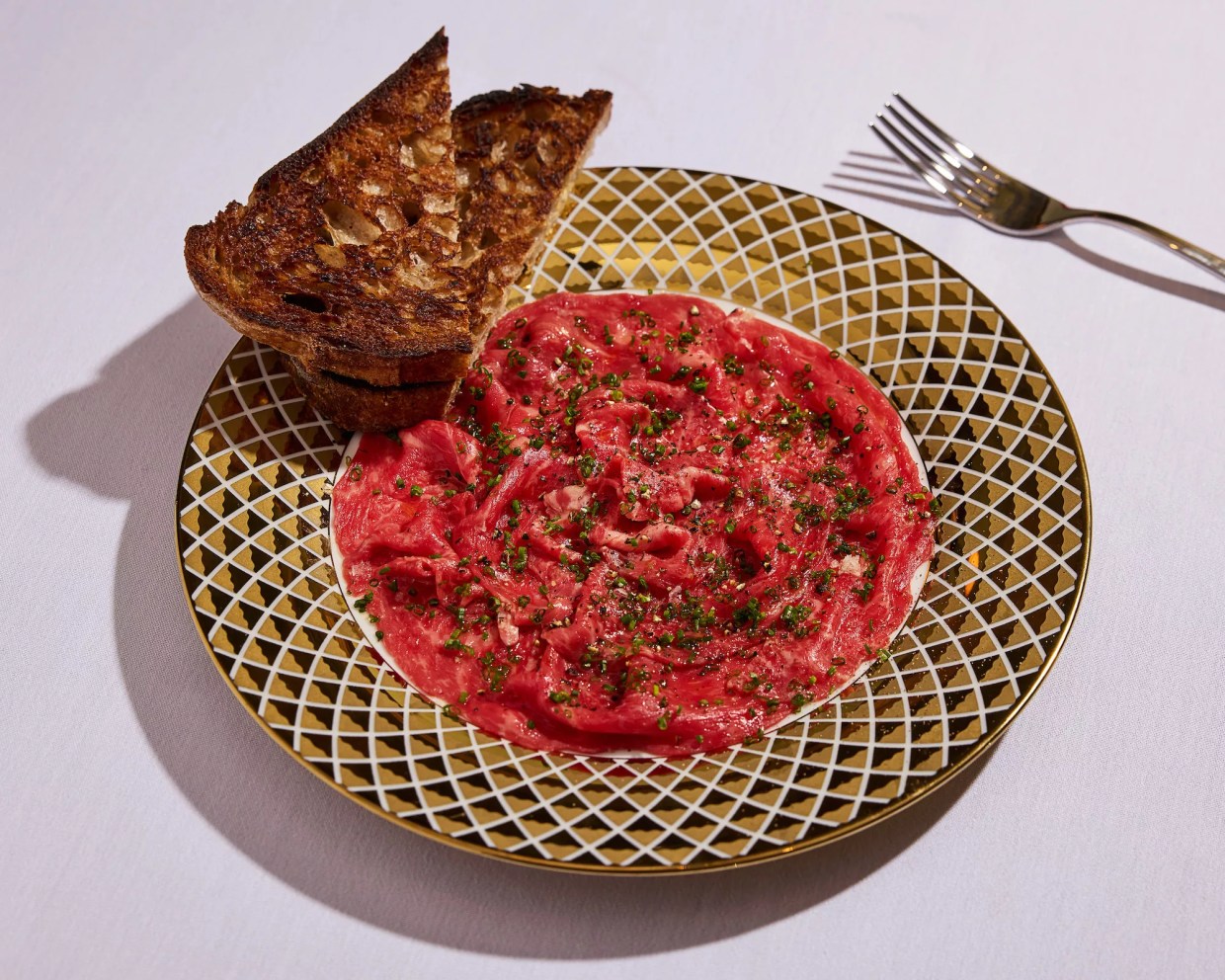 steak tartare in a ceramic serving dish with a side of toasted bread
