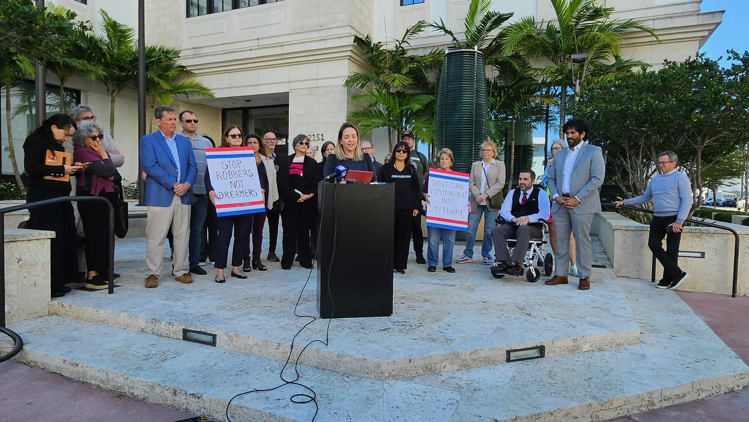 Laura Kelley, Chair of the Miami-Dade Democratic Party, speaks at a press conference while people stand behind her