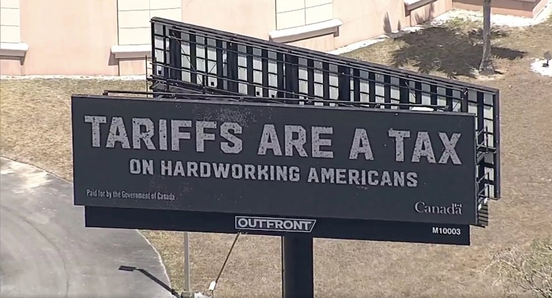 screenshot of an aerial shot of a billboard that reads: "TARIFFS ARE A TAX ON HARDWORKING AMERICANS."