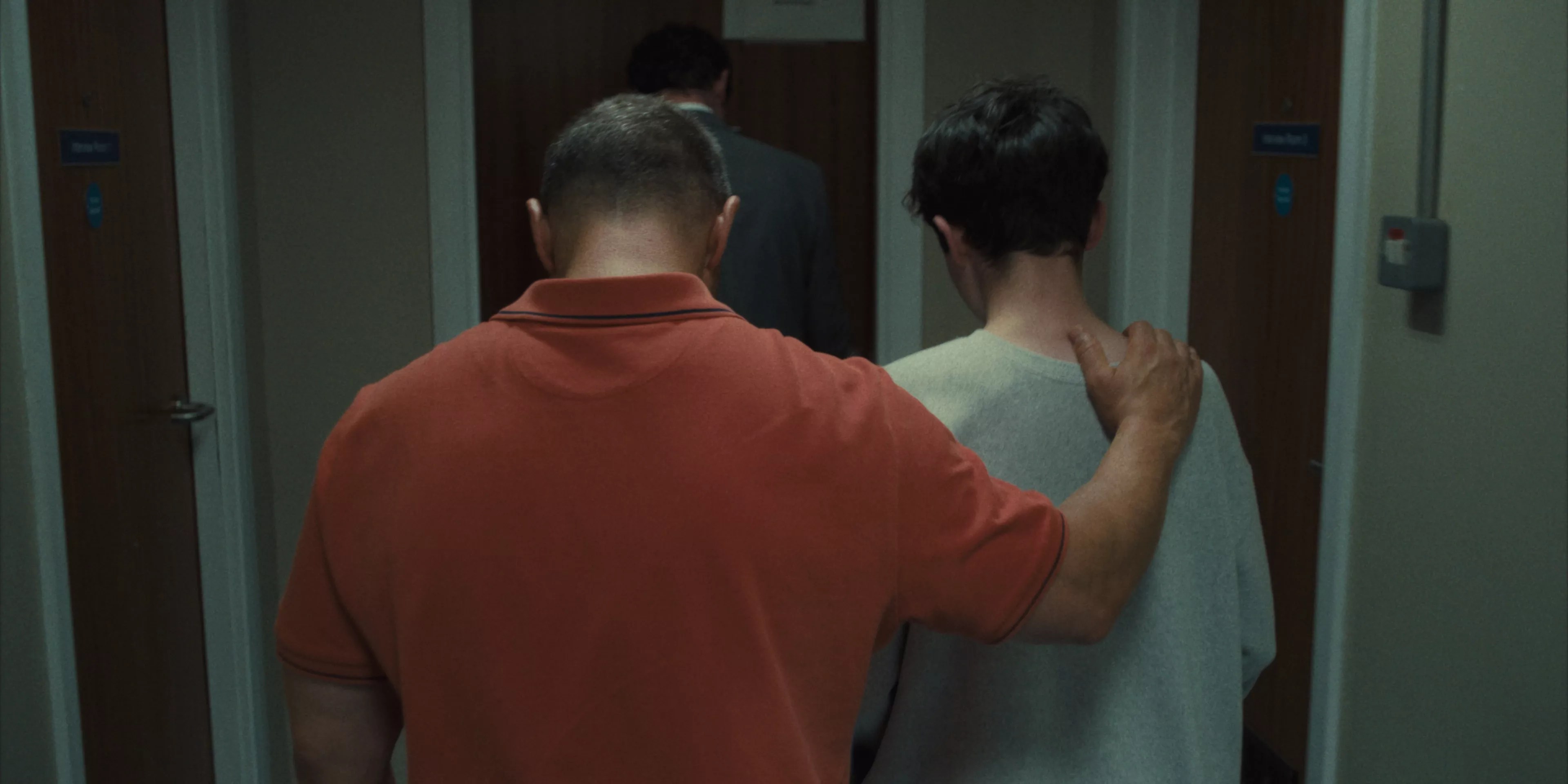 still from the Netflix show Adolescence. An adult man puts his arm around a young man