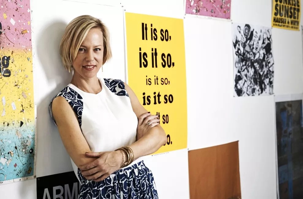 a woman stands in front of a wall of posters