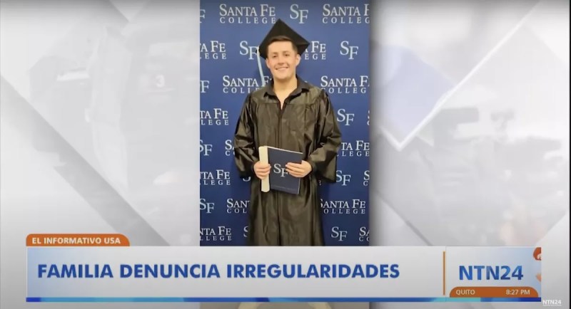 Photo of a young man in a black graduation cap and gown in front of a Santa Fe College banner.