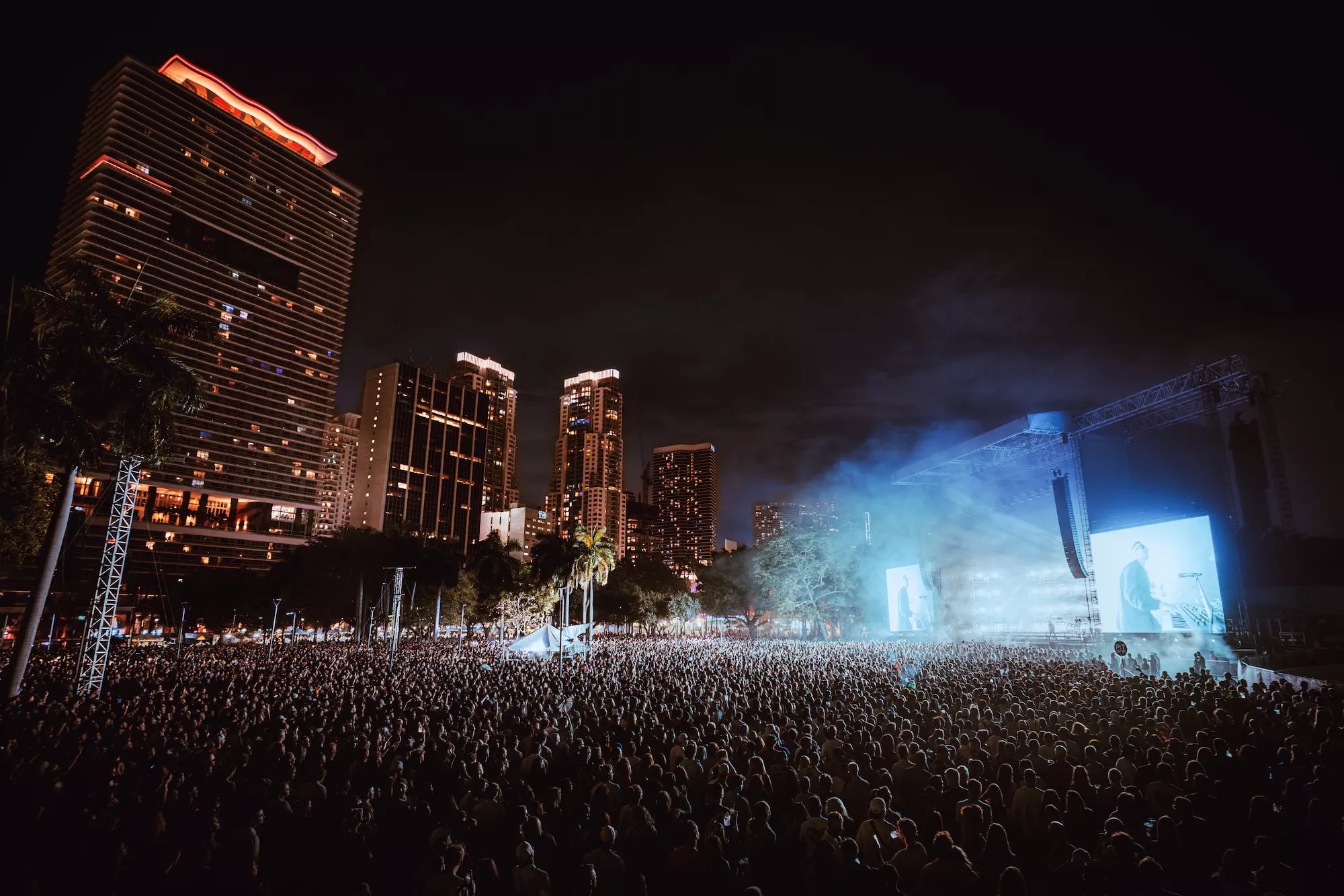 a huge crowd at an outdoor venue with the downtown Miami skyline in the background