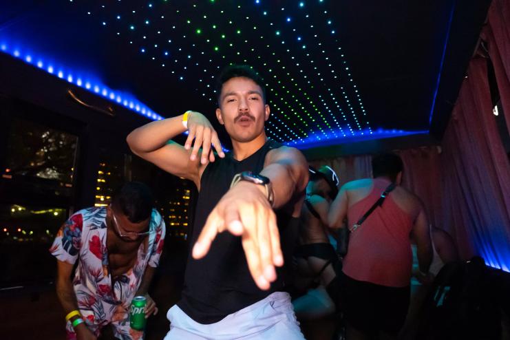 a man poses for the camera inside a neon-lit party bus
