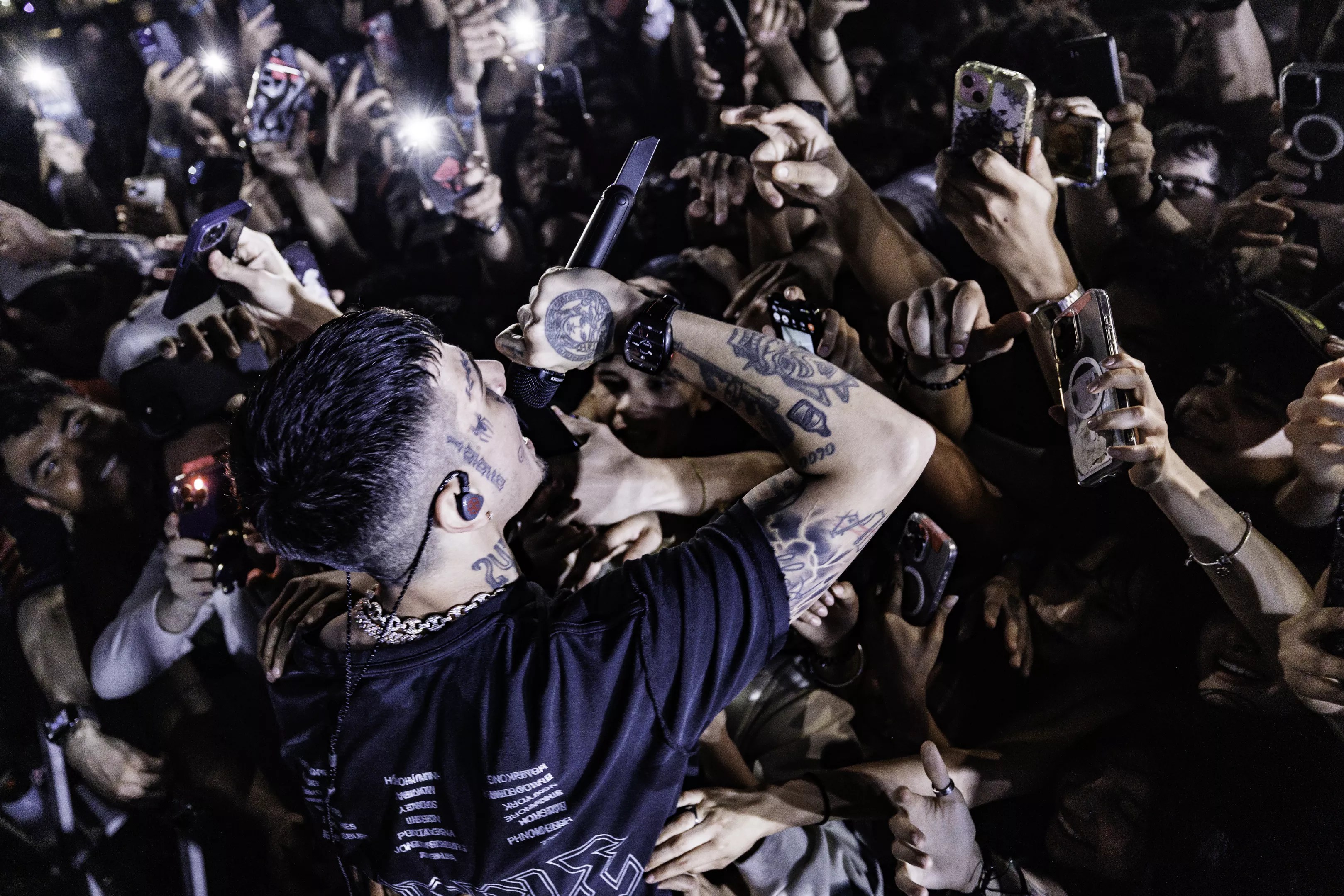 a rapper performs in front of a crowd holding phones
