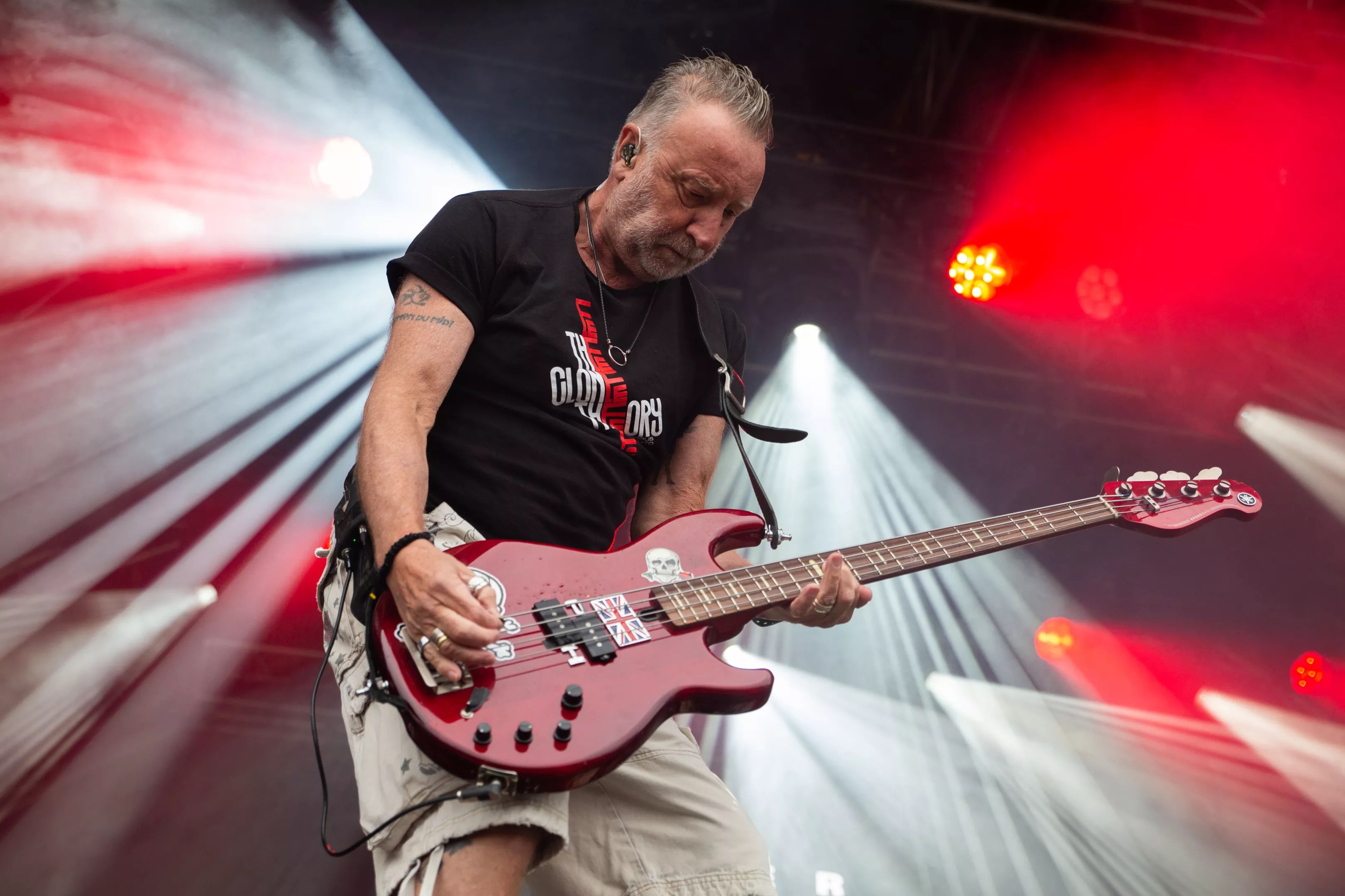 Peter Hook plays bass onstage with stage lights behind him