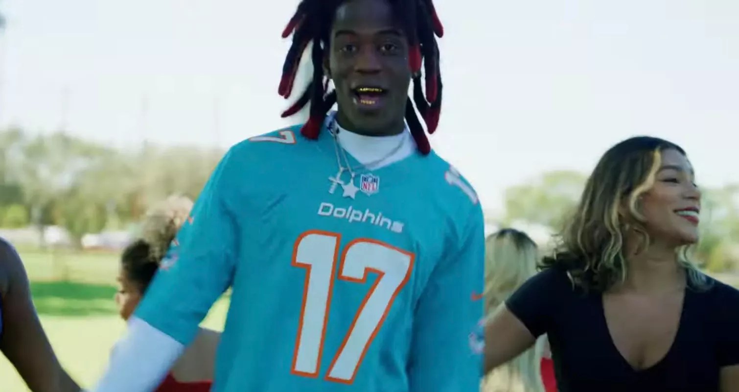 A photo of Cornelius Johnson wearing a Miami Dolphins jersey during a music video.