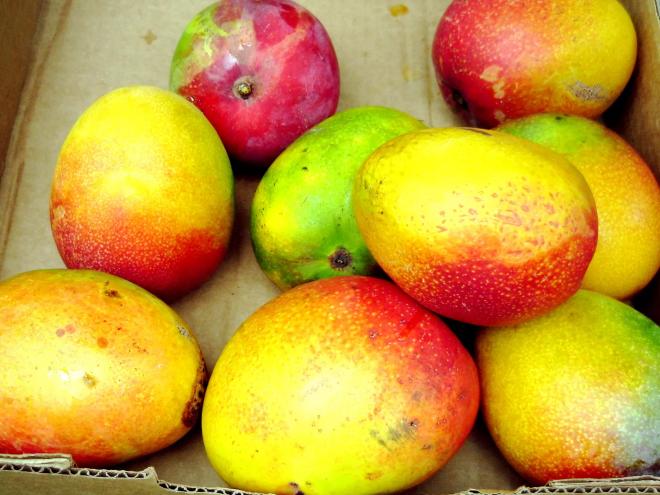 Several mangos sit in a pile.
