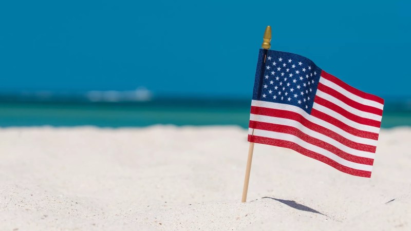 a small flag on a stake on a tropical beach