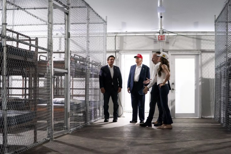Donald Trump, Ron DeSantis, Kristi Noem, Kevin Guthrie, Todd M. Lyons inside Alligator Alcatraz standing next to the caged bunk beds