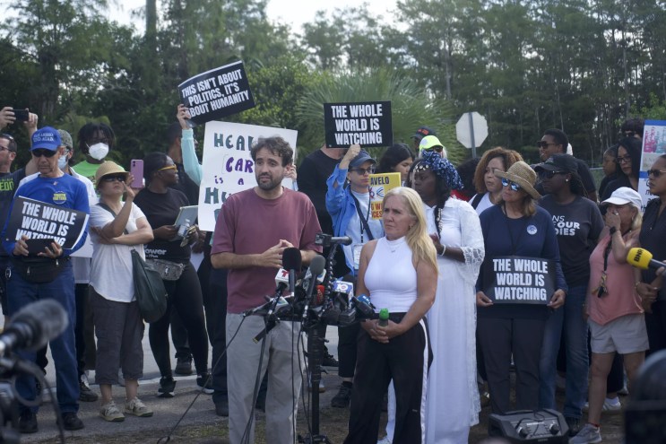 A woman speaks to reporters about her husband's experience in Alligator Alcatraz.