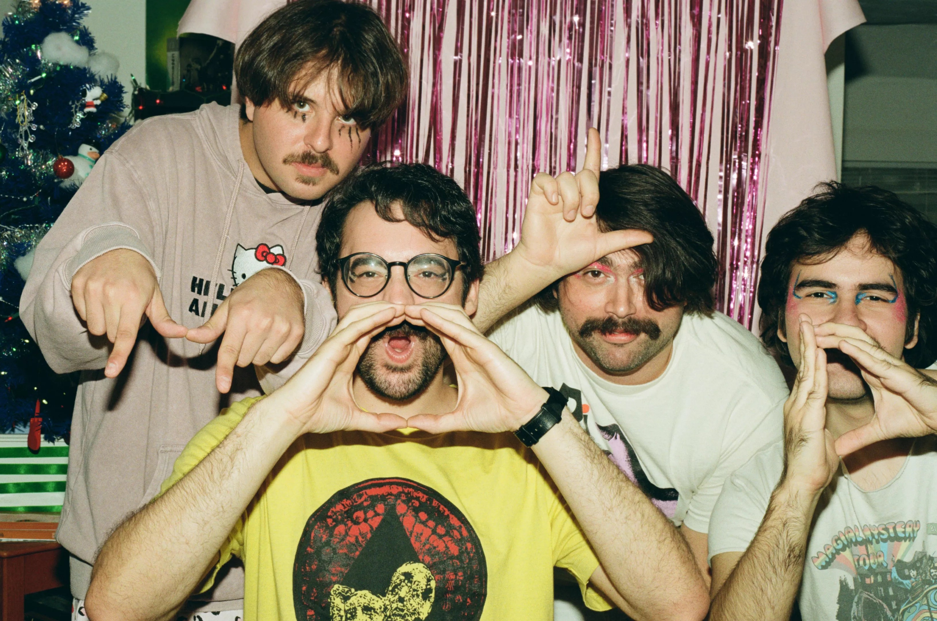 A group of four friends posing by a Christmas tree.