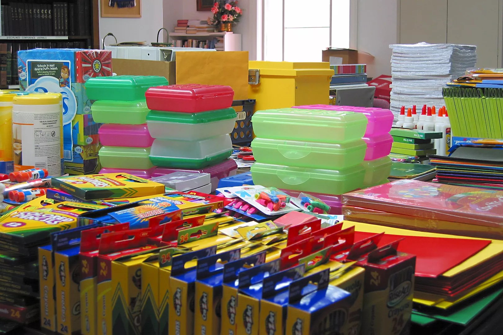 School supplies like crayons and pencil boxes sit on tables.