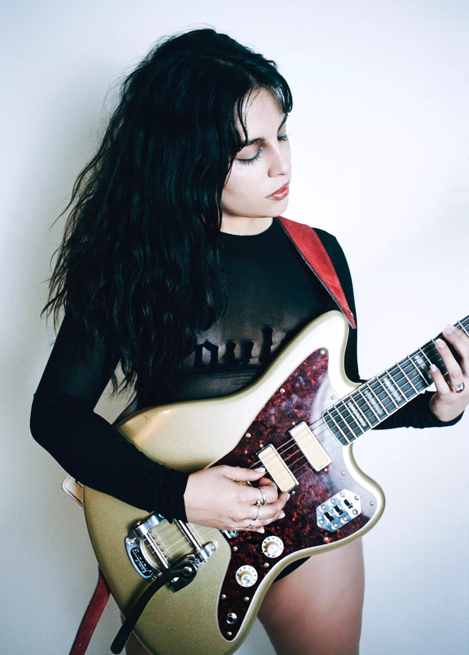 Woman with black hair playing guitar
