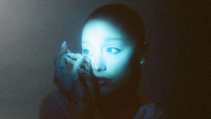 photo of Ariana Grande with most of her face illuminated in teal lighting