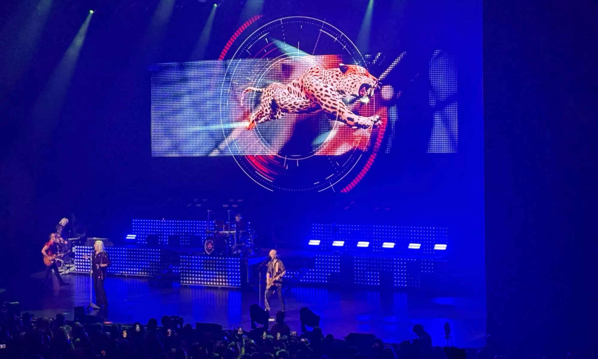 A picture of the band Def Leppard performing at the Hard Rock Live in front of a projection of a leppard.