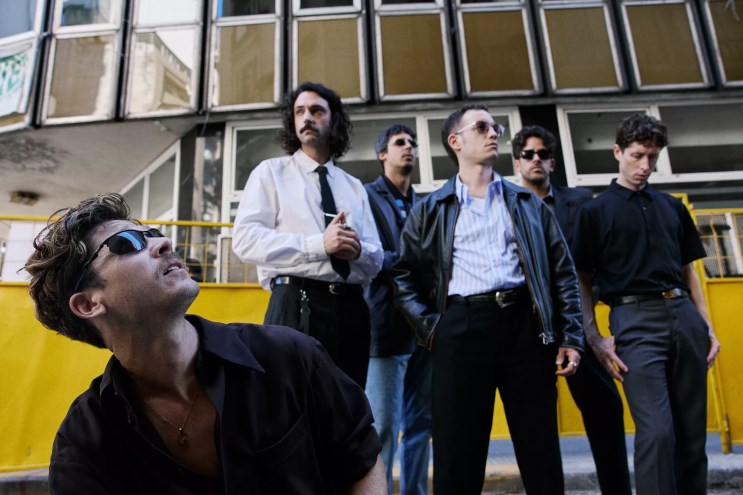 Image of a five-piece band posing in front of a building.