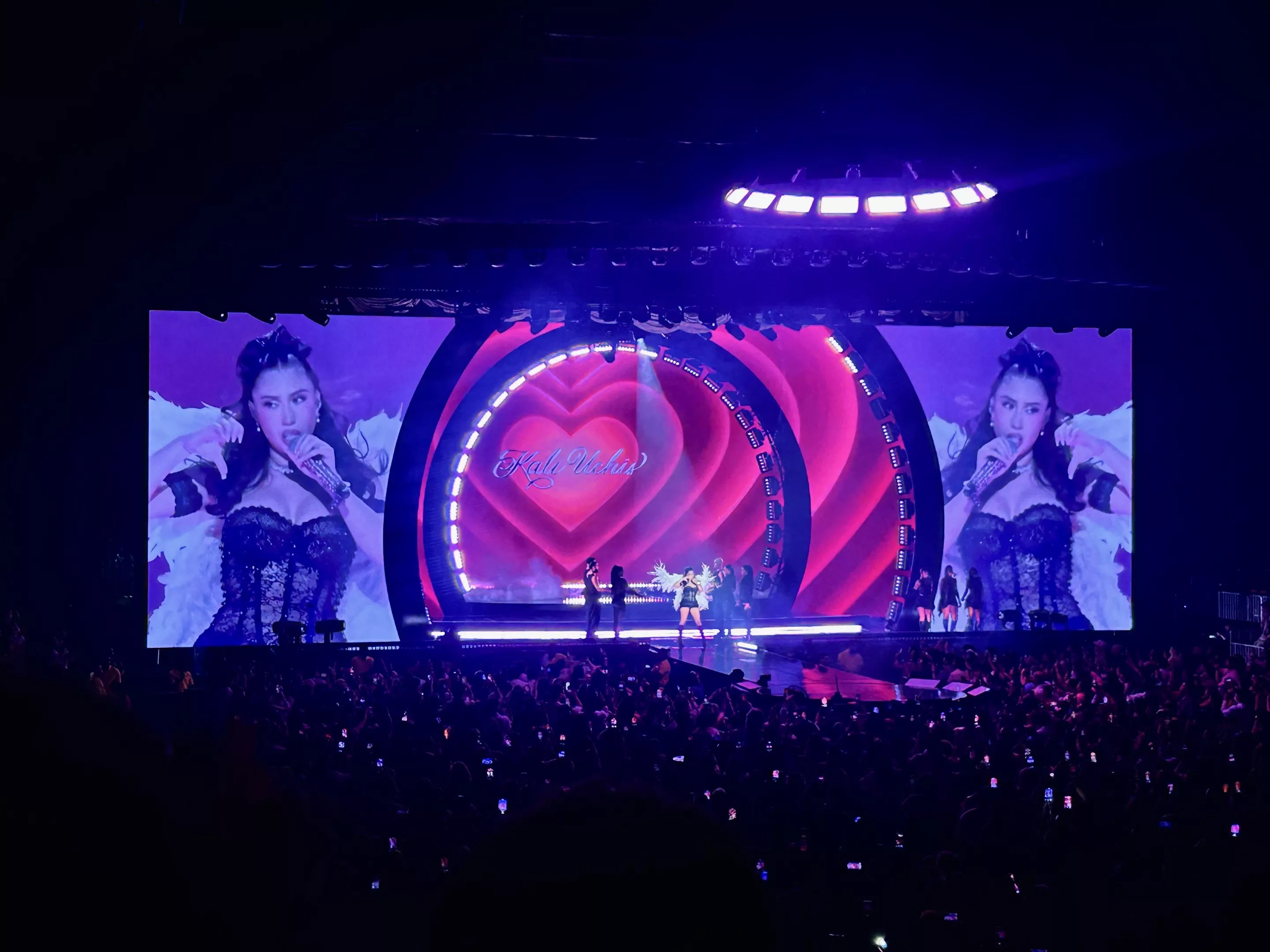 Picture of Kali Uchis singing on stage in front of a screen projecting a heart.