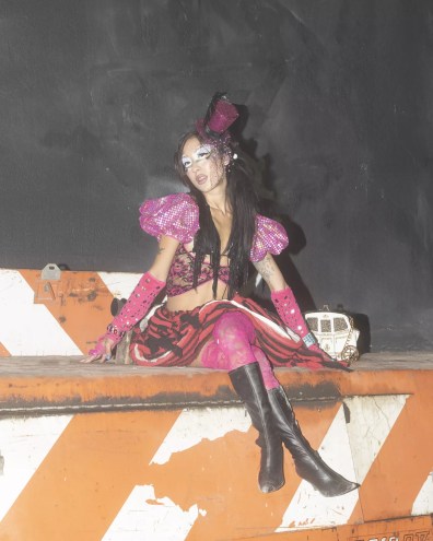 Picture of a woman wearing a pink costume sitting on a metal and concrete structure.