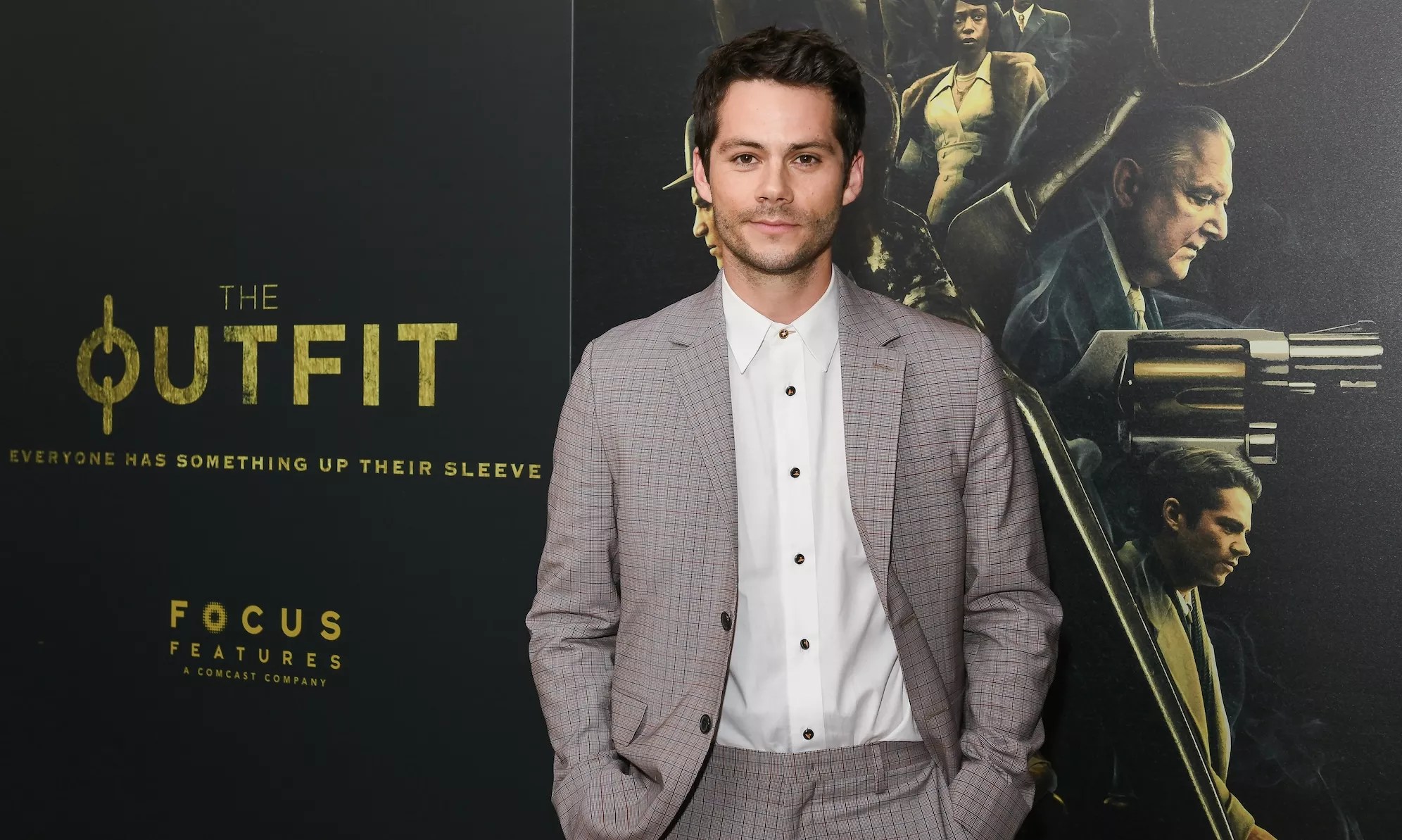 Actor Dylan O'Brien wears a suit on a red carpet at a film premiere.