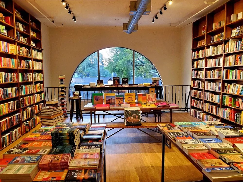 the inside of a bookstore with an arched doorway leading to book lined shelves on either side of a light filled room