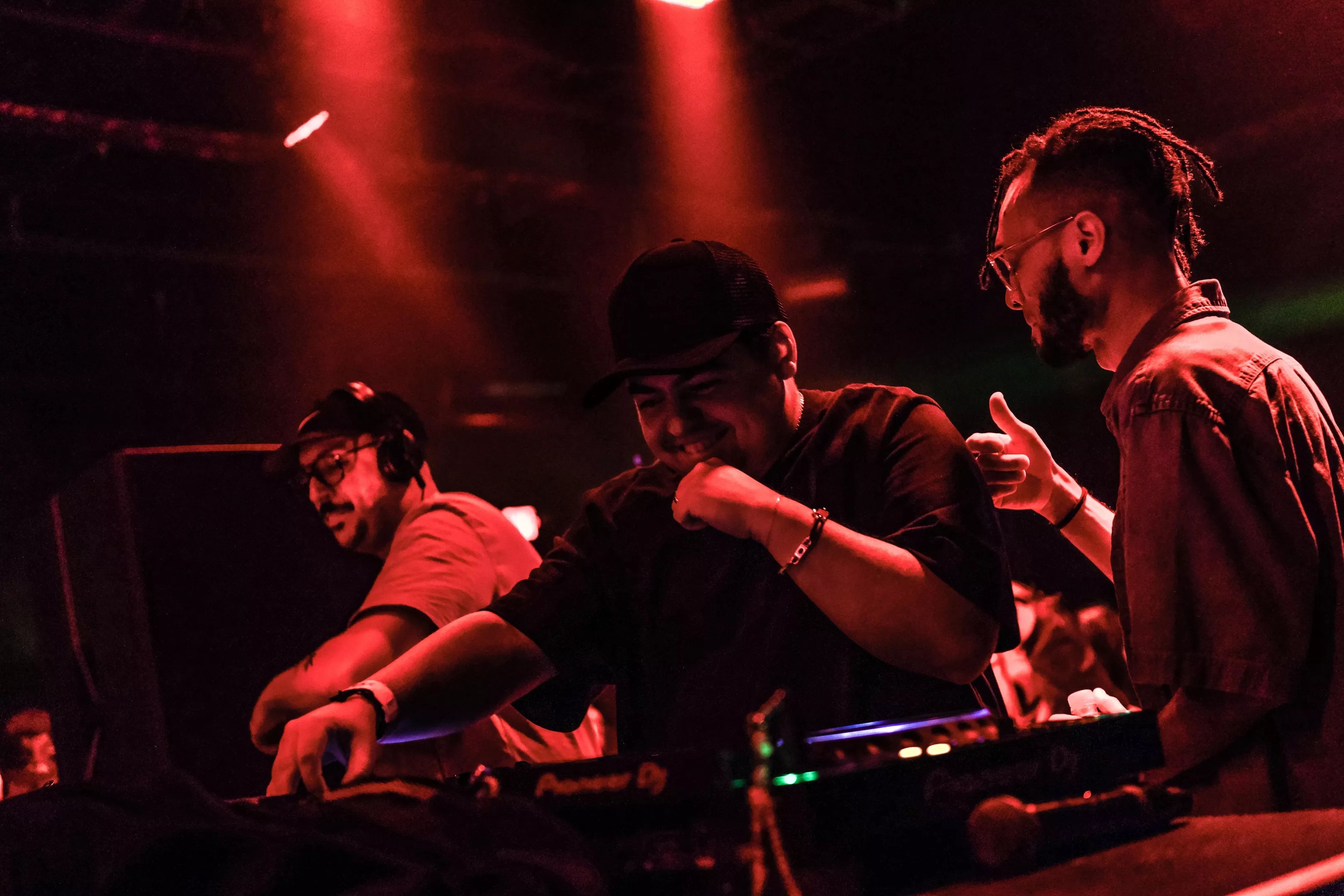 A DJ performing under red lights.
