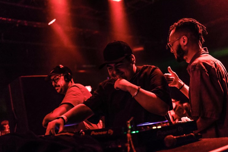 A DJ performing under red lights.