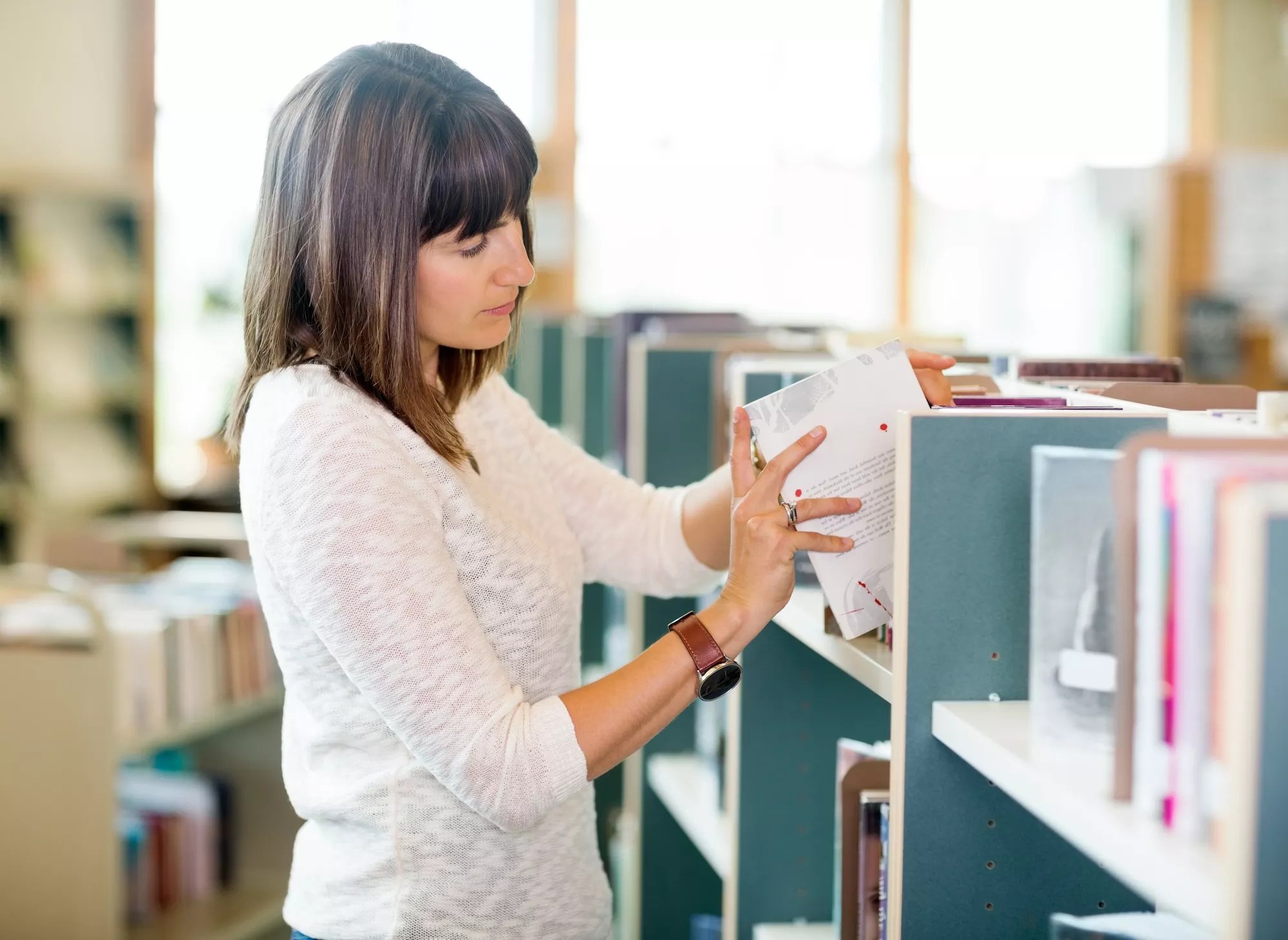 stock photo of a woman shelving books in a library